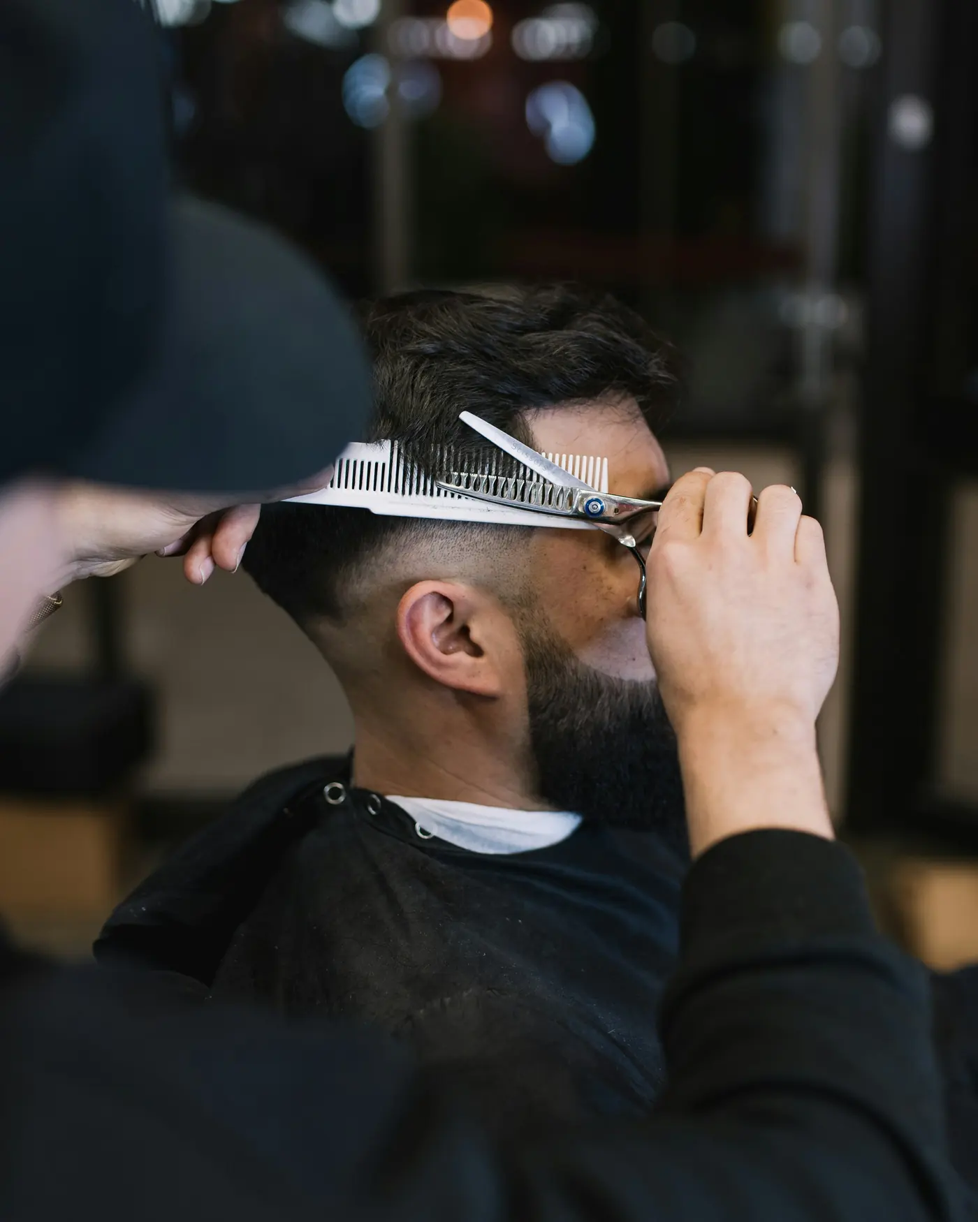 Un hombre cortando el cabello de otro hombre con un par de tijeras